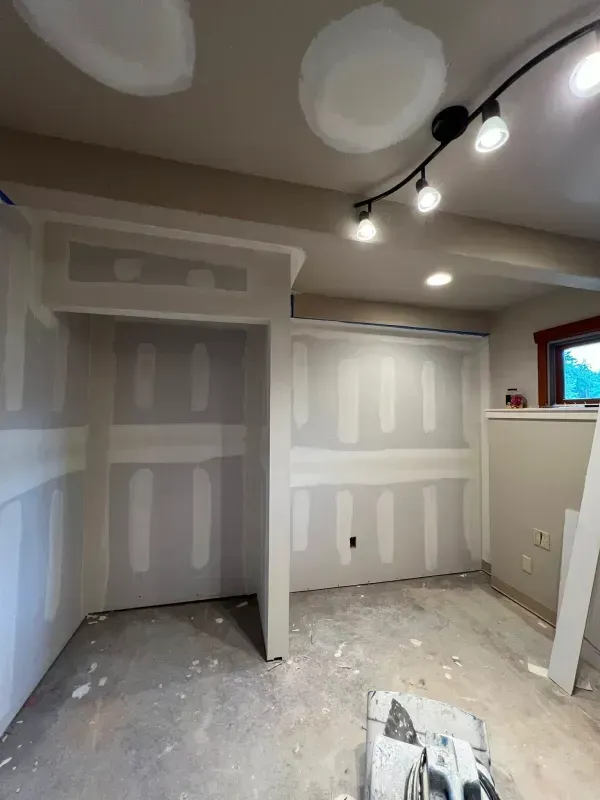 Room under construction with drywall and exposed studs; track lighting.