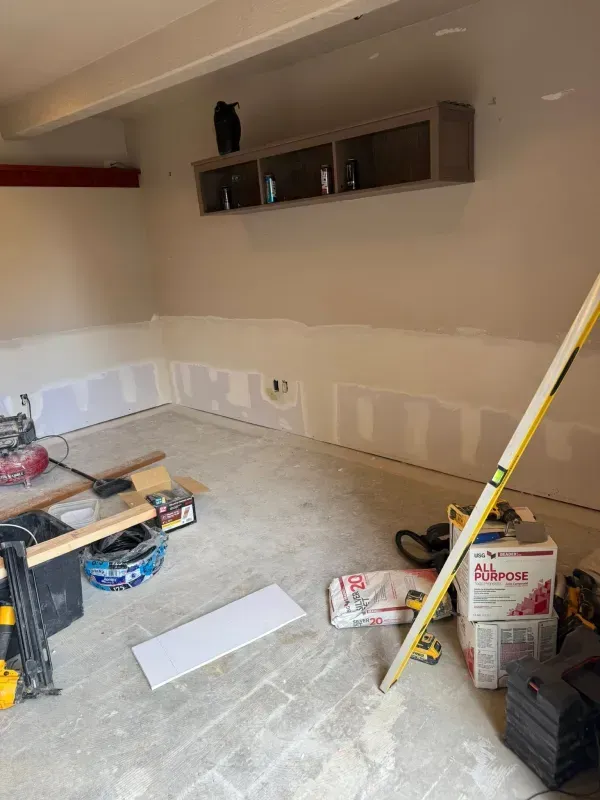 Interior view of a room under construction with drywall along the walls and tools scattered about.