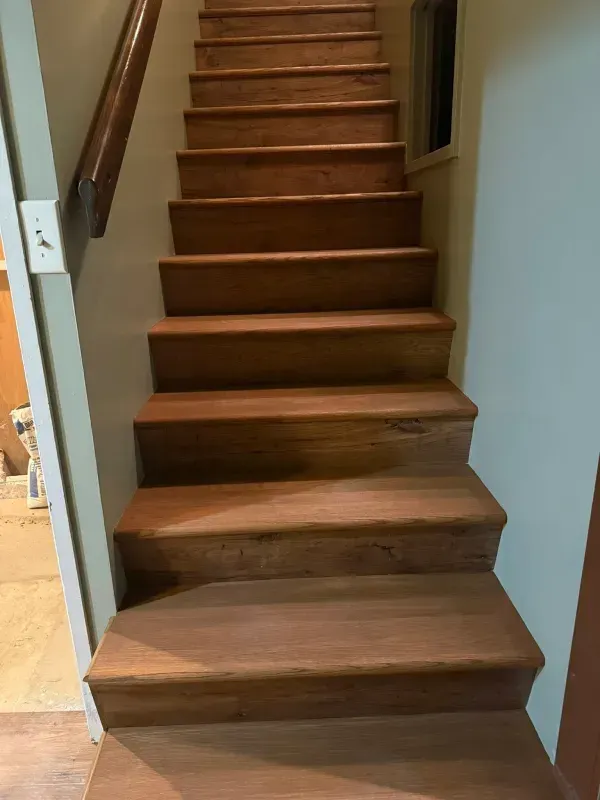 Wooden staircase with a dark stain, ascending. Handrail on the left.