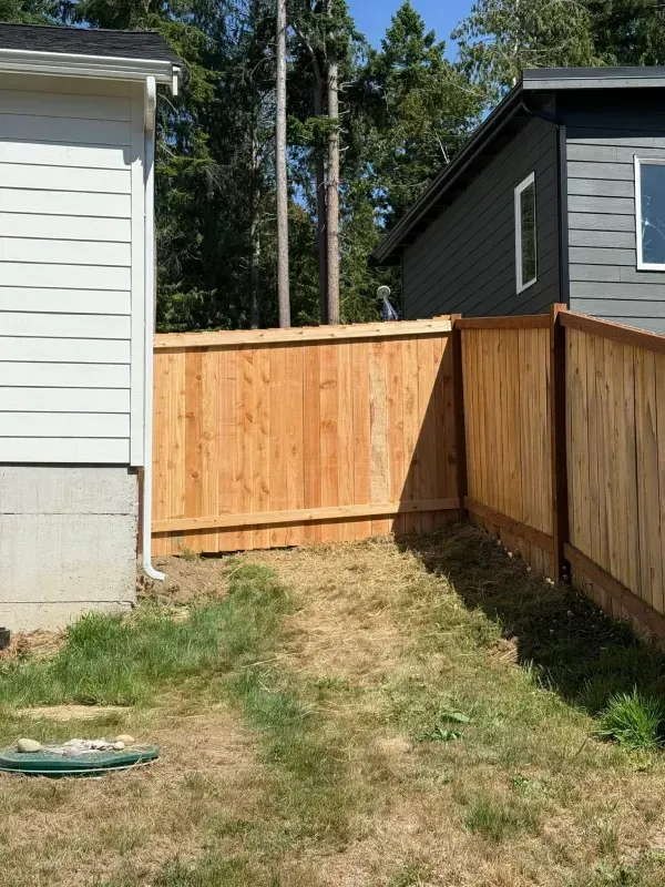 Wooden fence between two houses, separating a grassy area.