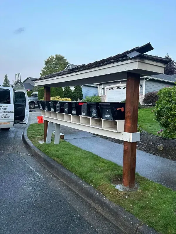 Mailboxes under a covered wooden structure next to a residential street with a vehicle visible.