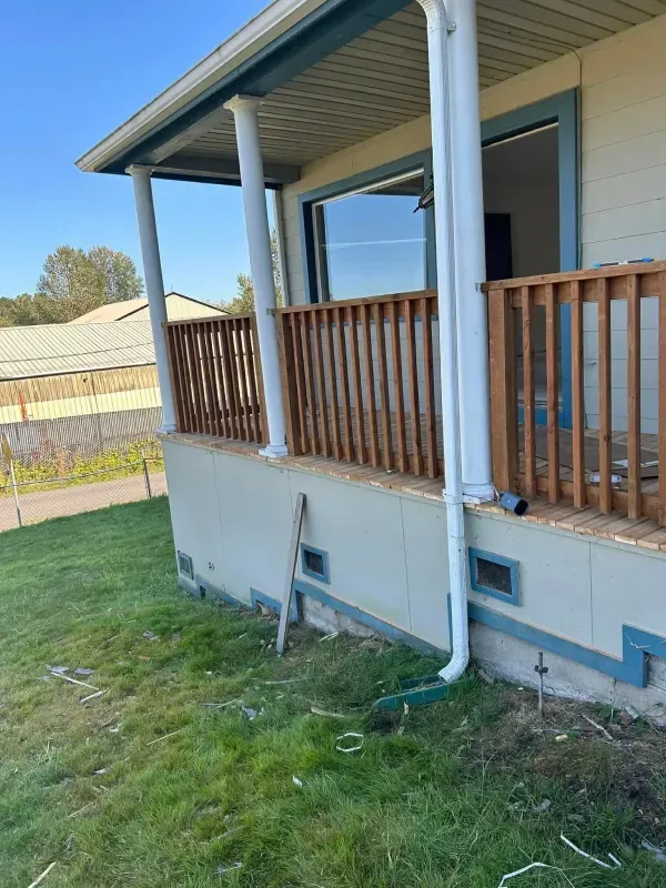 House exterior with porch, wood railing, and downspout.