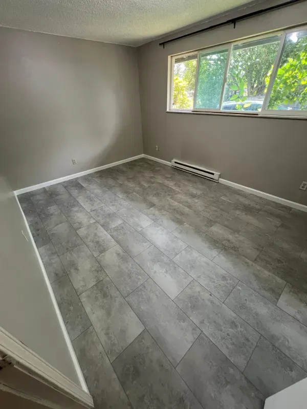 Gravel path beside a yellow house, leading to a backyard with greenery and an above-ground pool.