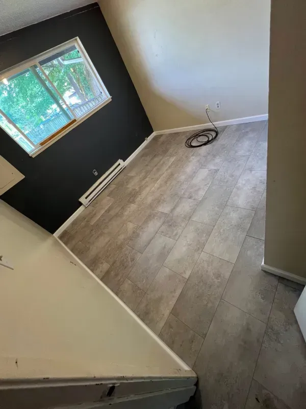 Room with gray flooring, black accent wall, window, and a heating unit.