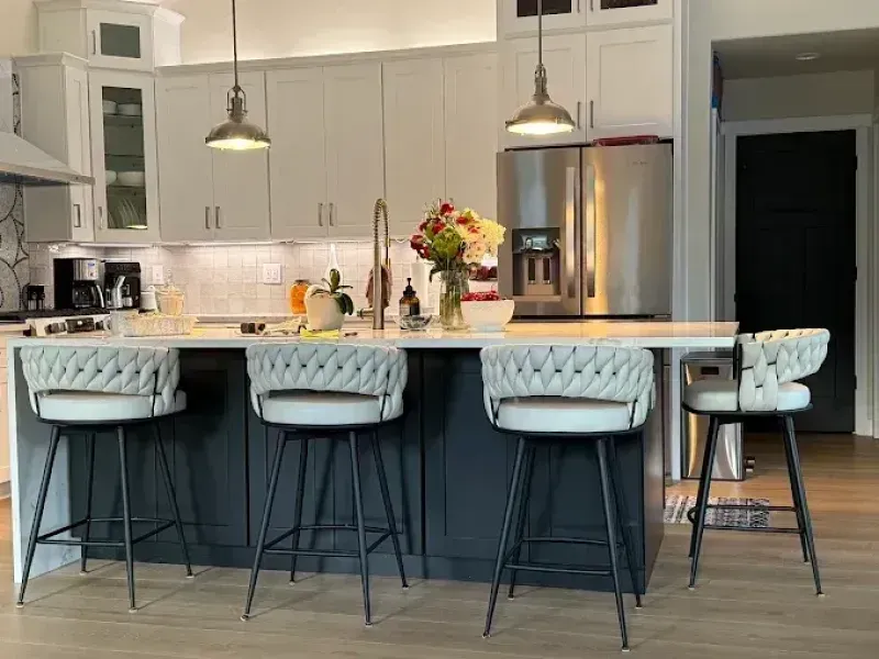 Kitchen with white and blue cabinets, island with four bar stools, and fresh flowers.
