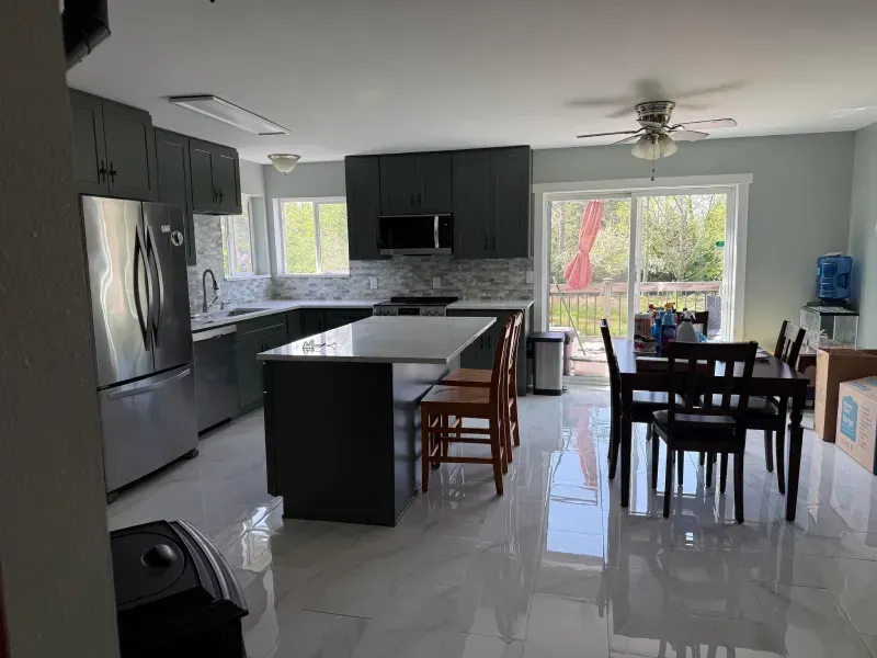 Modern kitchen with gray cabinets, island, stainless steel appliances, and dining area.