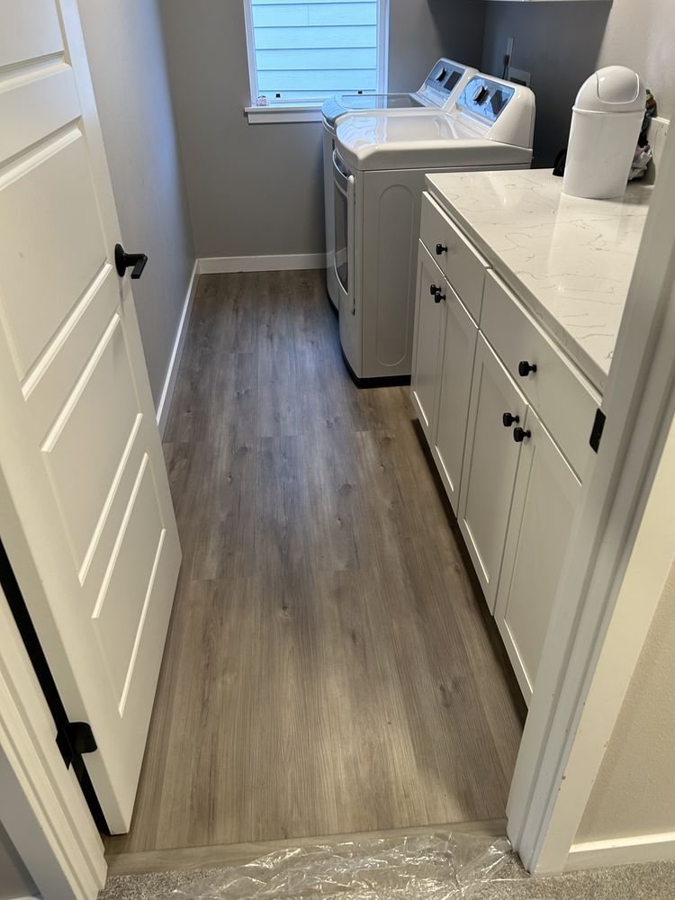 Laundry room with white cabinets, washing machine, and light wood-look flooring.