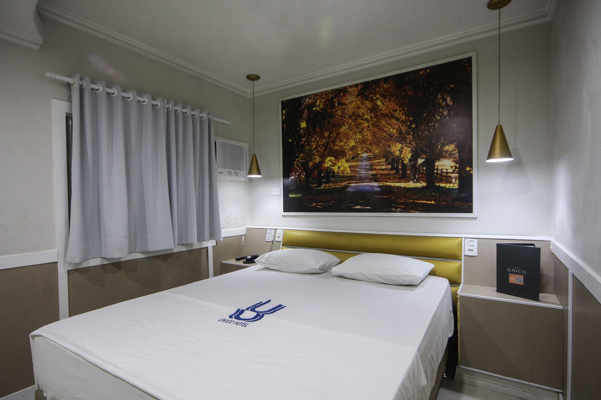 Um quarto de hotel com uma cama e um quadro na parede.