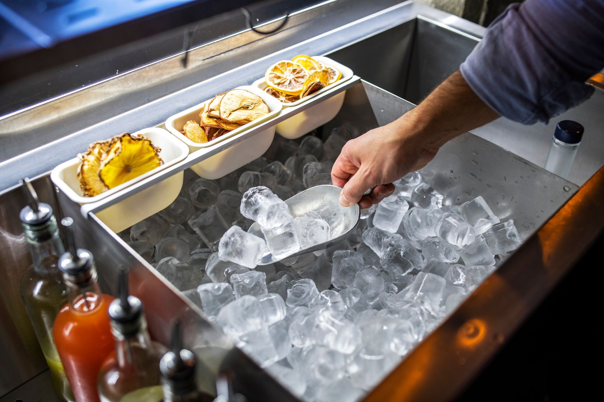 Bartender putting ice cubes in a glass.