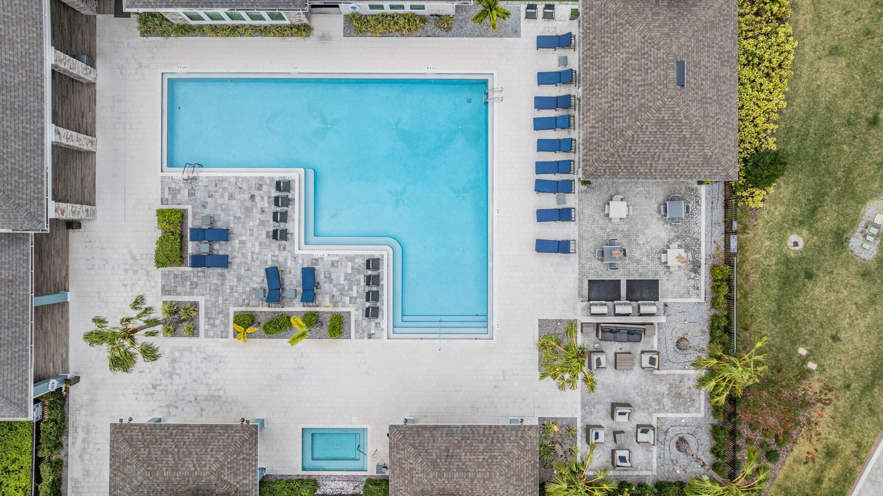 Aerial view of a modern apartment complex with parking lots, trees, and landscaped walkways.