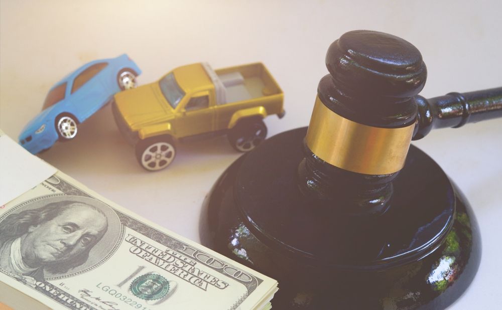 Toy cars, gavel, and cash bundle, suggesting a legal or financial context related to vehicles.