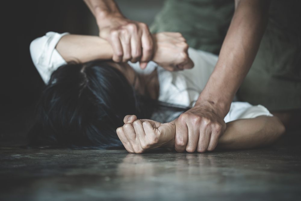 Person's hands gripping another person's arms, body on floor; possible assault.