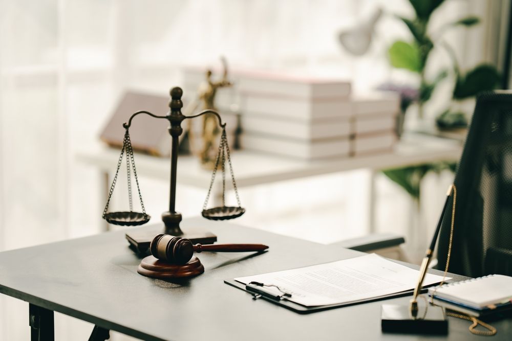 Scales of justice, gavel, and documents on a desk, representing law and justice.