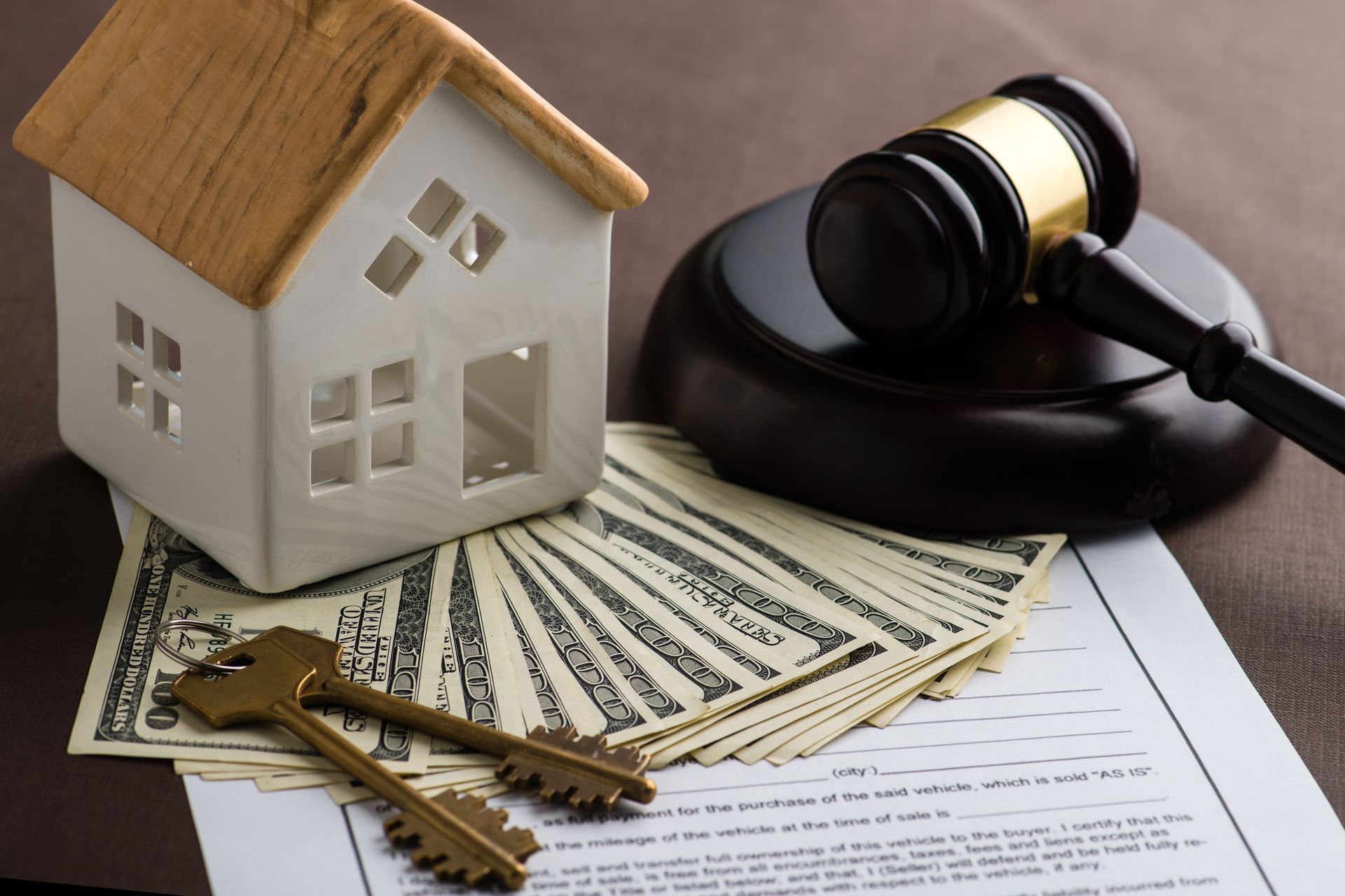 A model house is sitting on top of a pile of money next to a judge 's gavel.