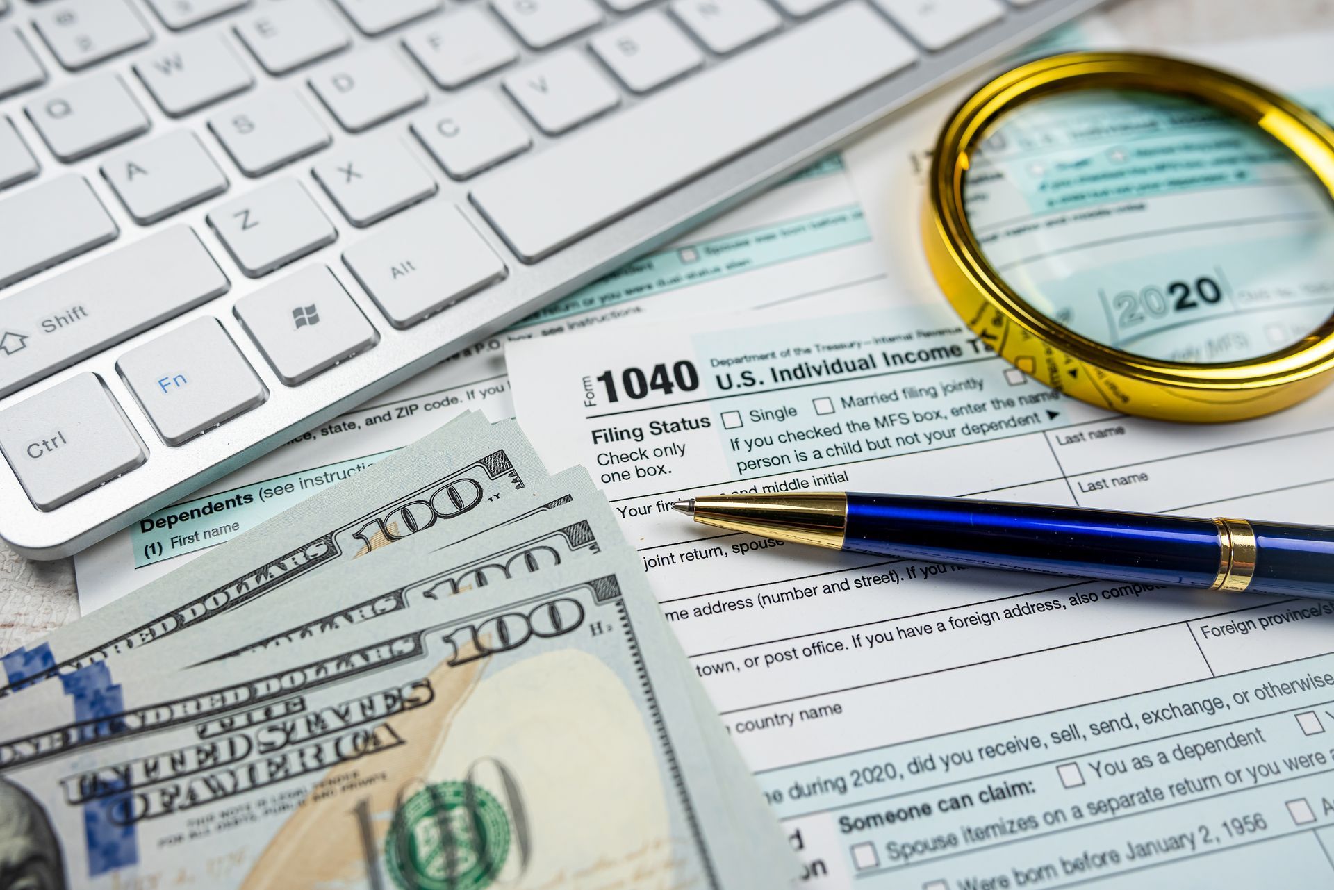 A pen is sitting on top of a tax form next to a keyboard.