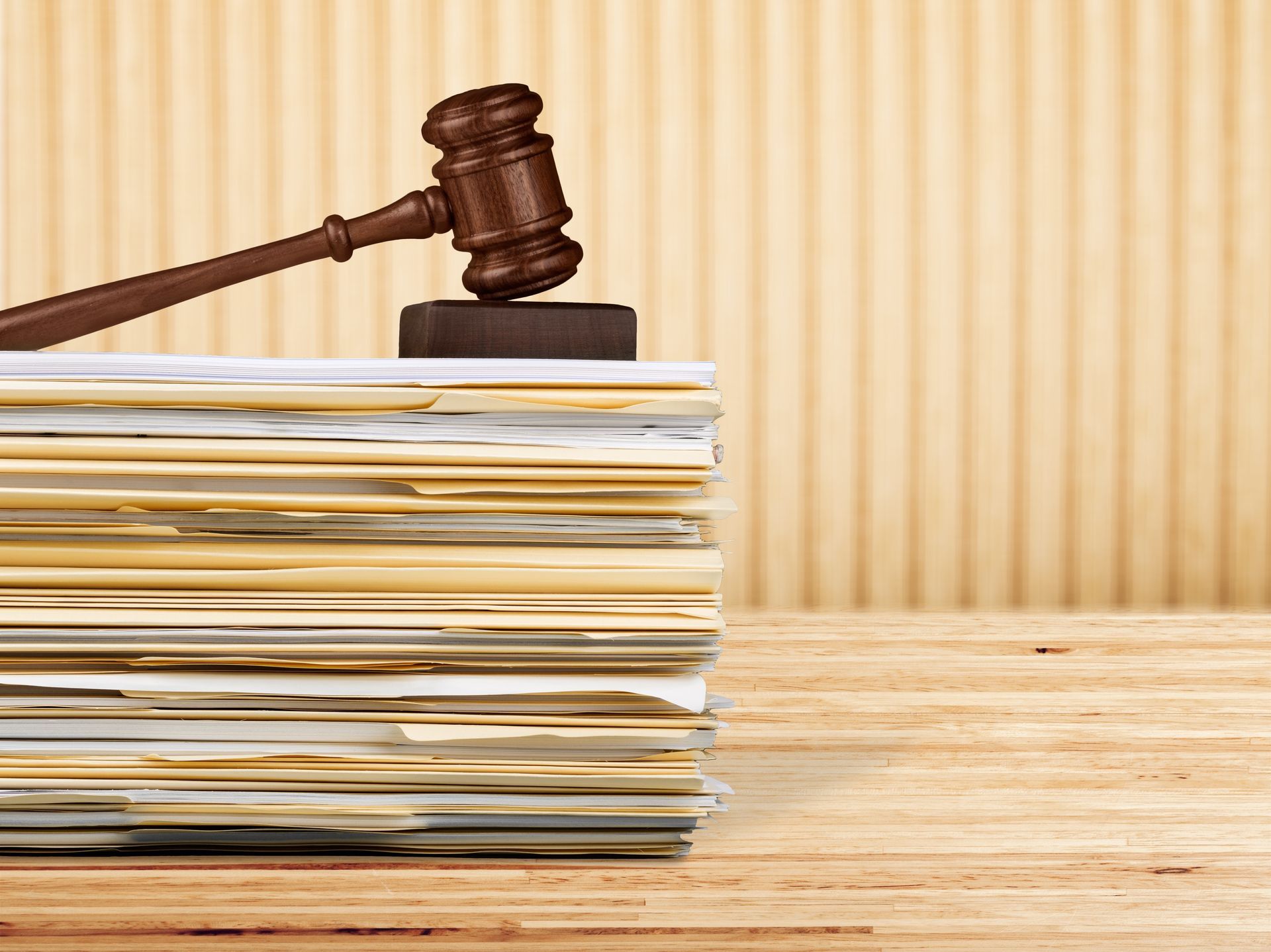 A judge 's gavel is sitting on top of a stack of papers on a wooden table.