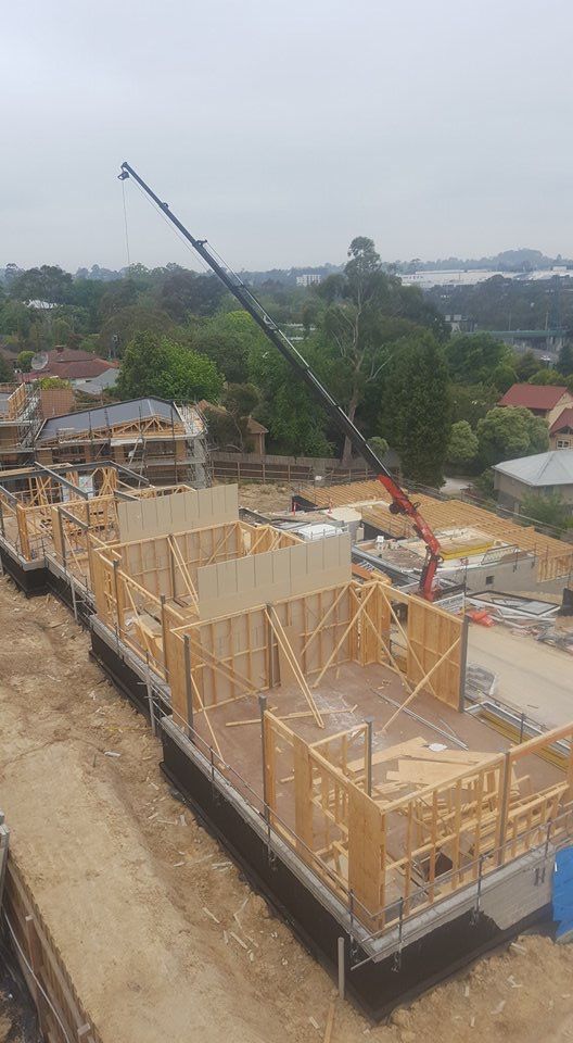 A crane is lifting a wooden structure on a construction site.