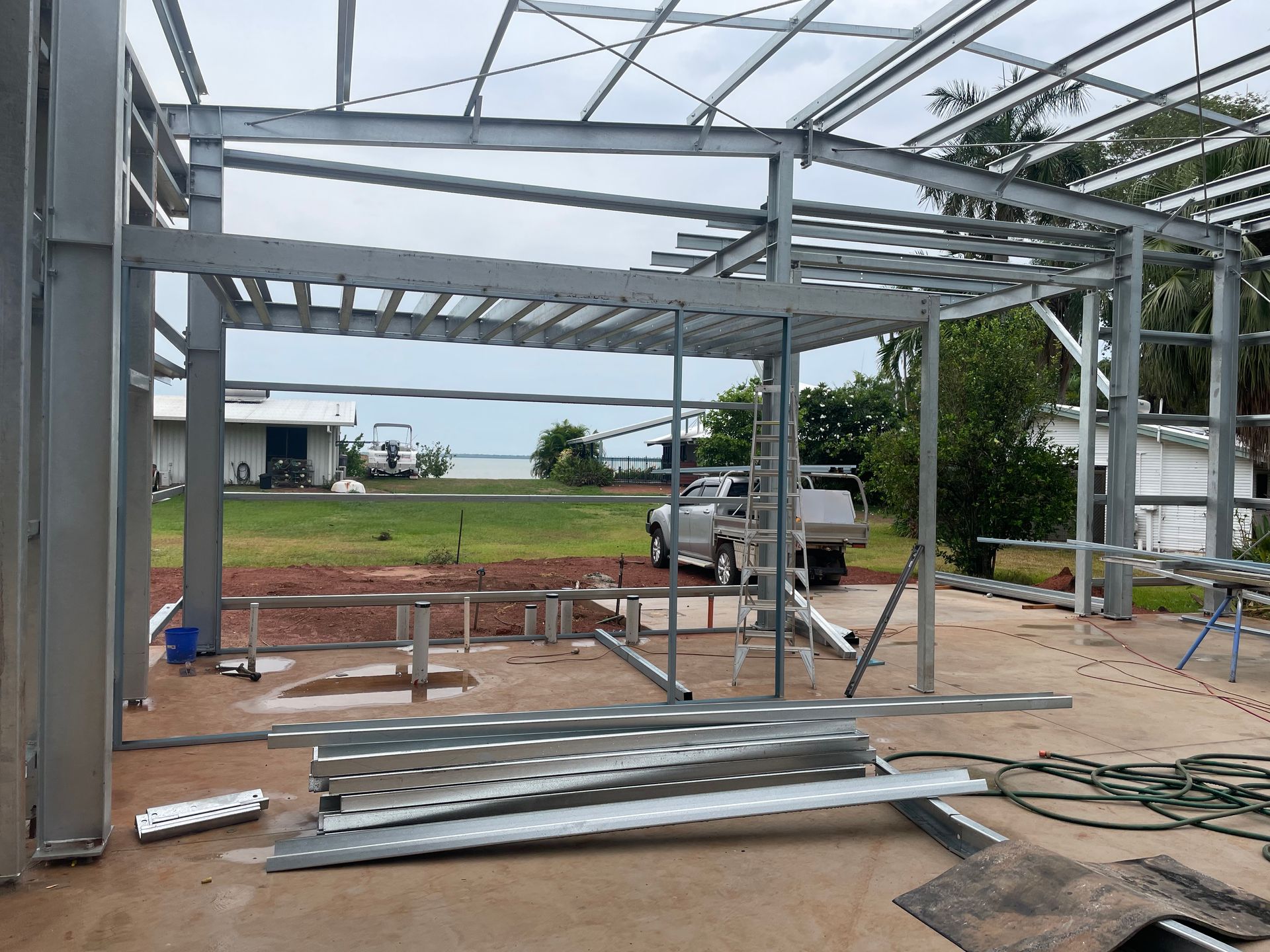 A metal structure is being built in a yard with a truck parked in the background.
