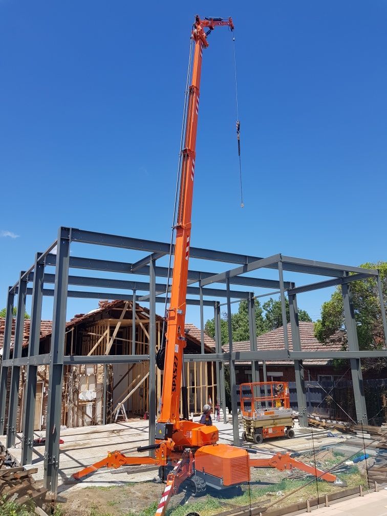 A large orange crane is sitting in front of a building under construction.