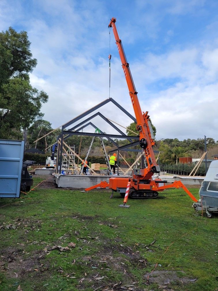 A crane is lifting a structure in a grassy field.