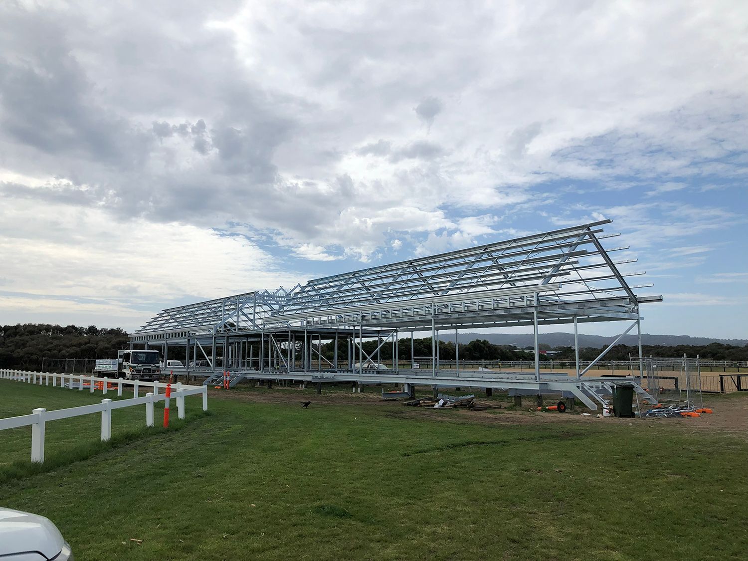 A large metal structure is being built in a grassy field.