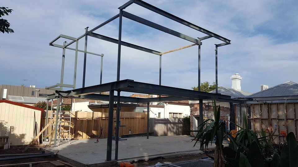 A large metal structure is being built in the backyard of a house.