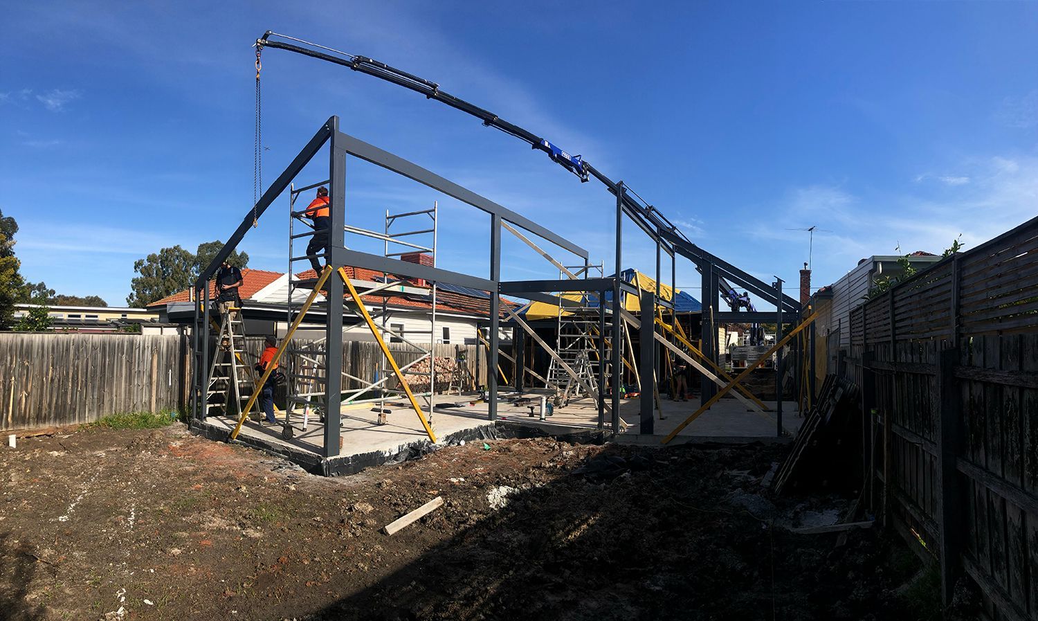 A large metal structure is being built in a backyard.