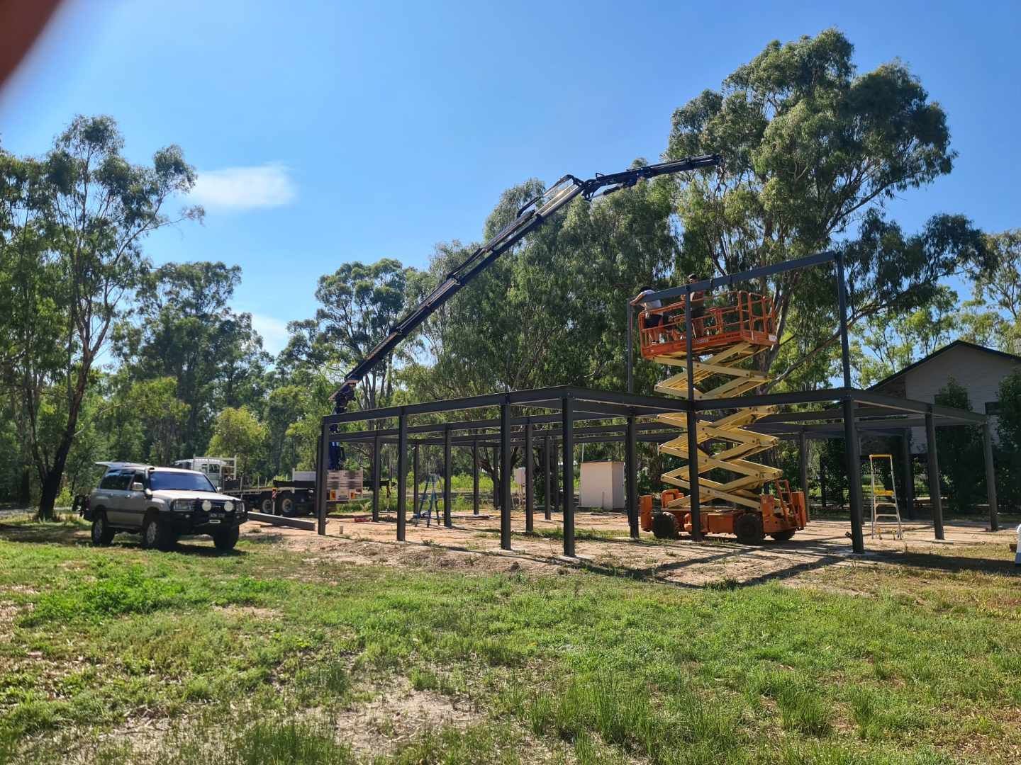 A crane is lifting a metal structure in a field.