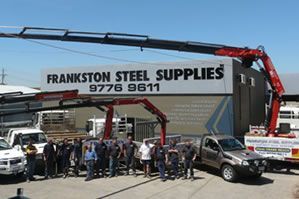 A group of people standing in front of a frankston steel supplies sign