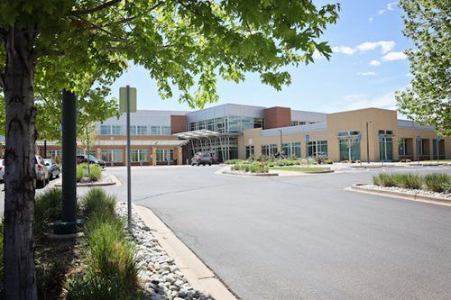 Modern medical building with parking lot and trees. Blue sky.