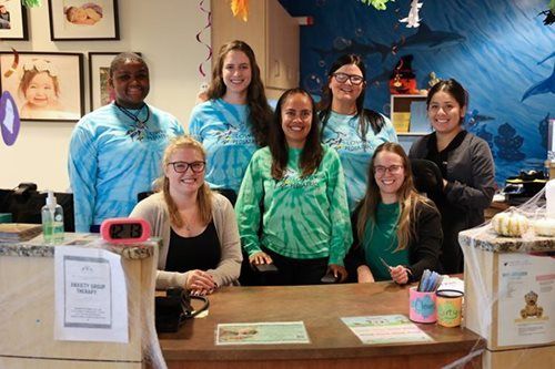 Group of people in tie-dye shirts behind a reception desk, possibly at a medical office.