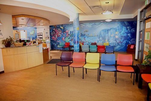Waiting room with colorful chairs, an underwater mural, and a reception desk.