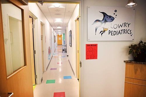 Hallway in Lowry Pediatrics with colorful floor tiles and a sign with a shark illustration.