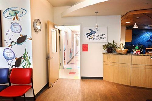 Pediatrician's office interior: reception desk, waiting area with chairs, hallway, and colorful wall art.