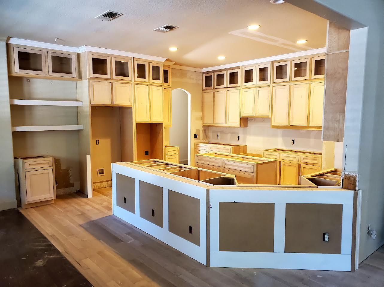 Kitchen under construction with unfinished light cabinets and an island.