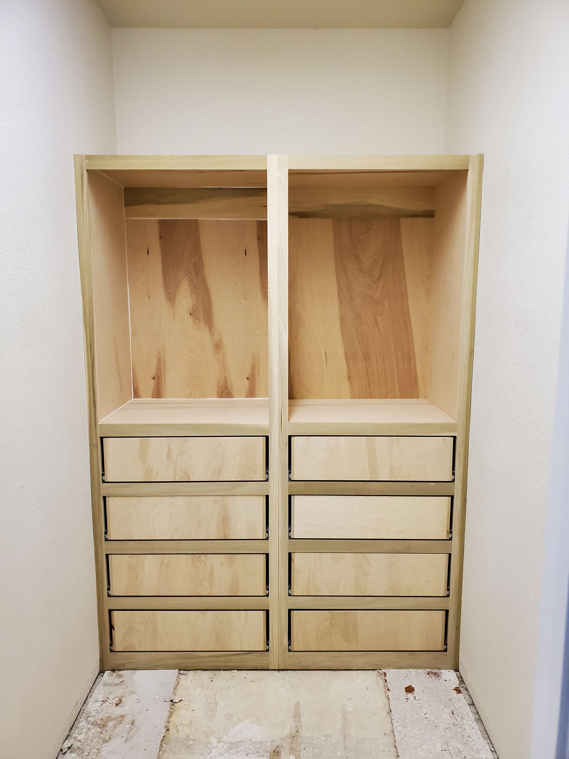 Unfinished wooden closet with two sections: drawers below shelves with tall open spaces above.