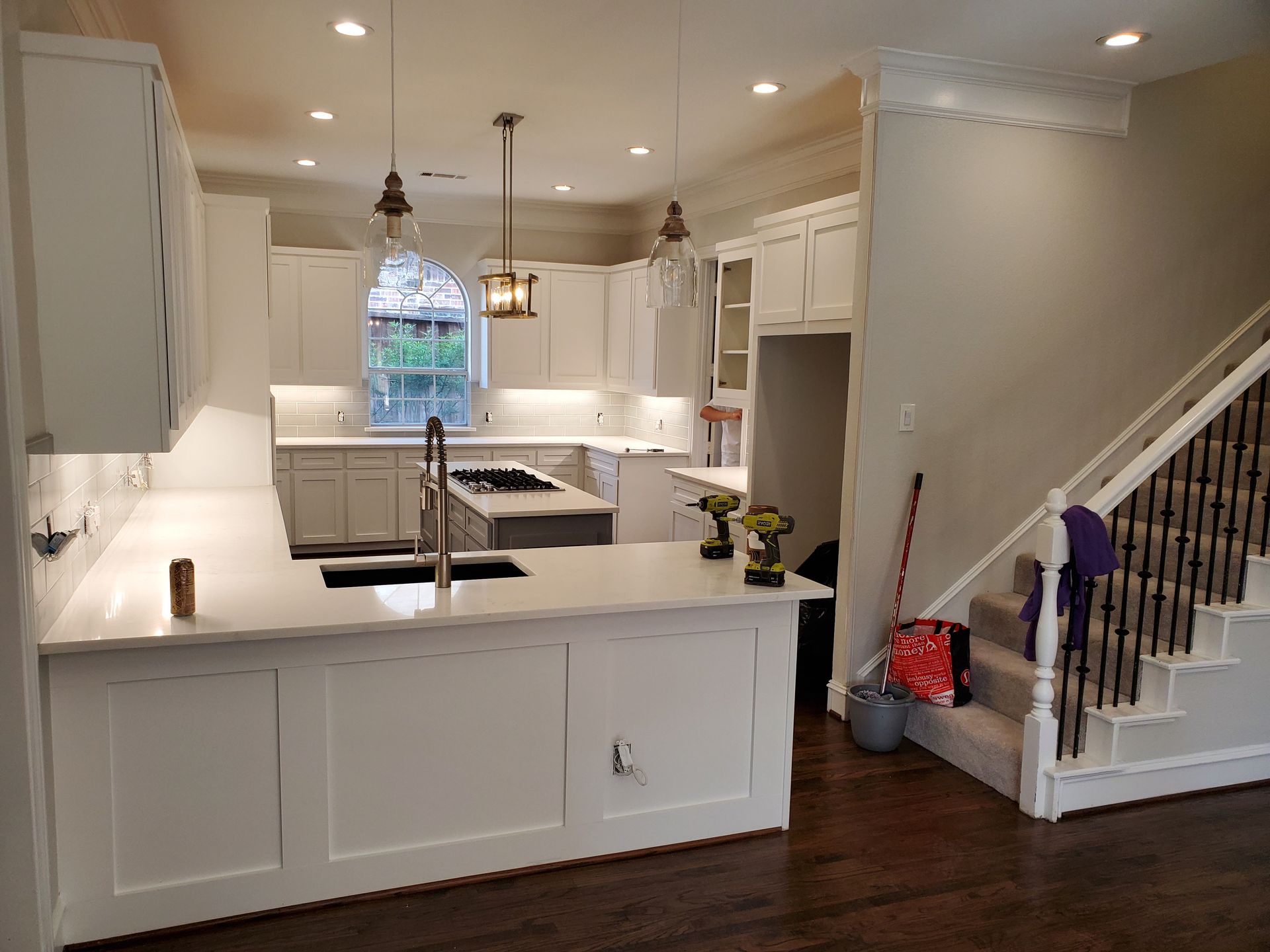 Spacious, modern kitchen with white cabinets, countertops, and island. A staircase is visible on the right.