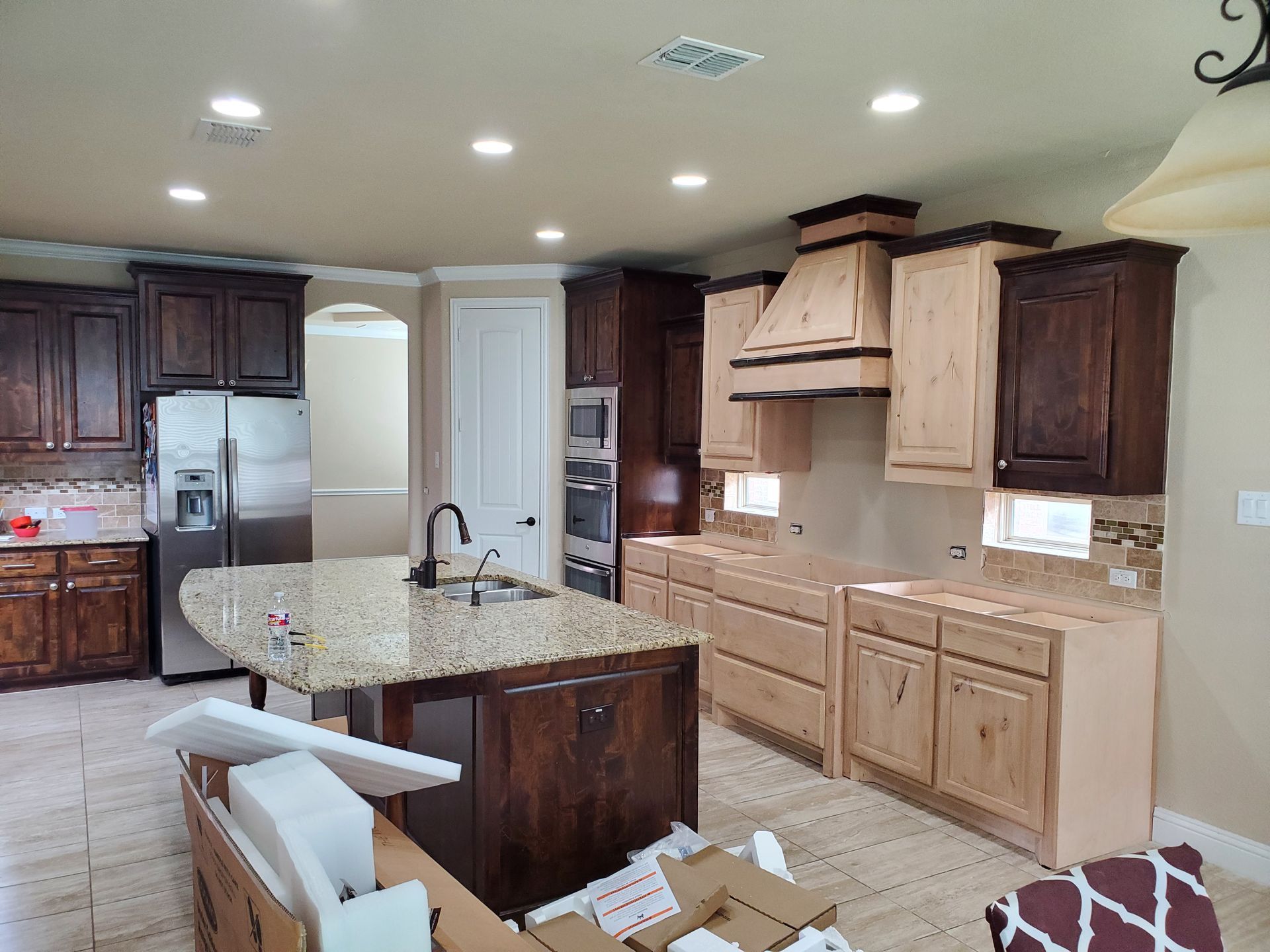 A kitchen under renovation. Features dark and light wood cabinets, a granite countertop island