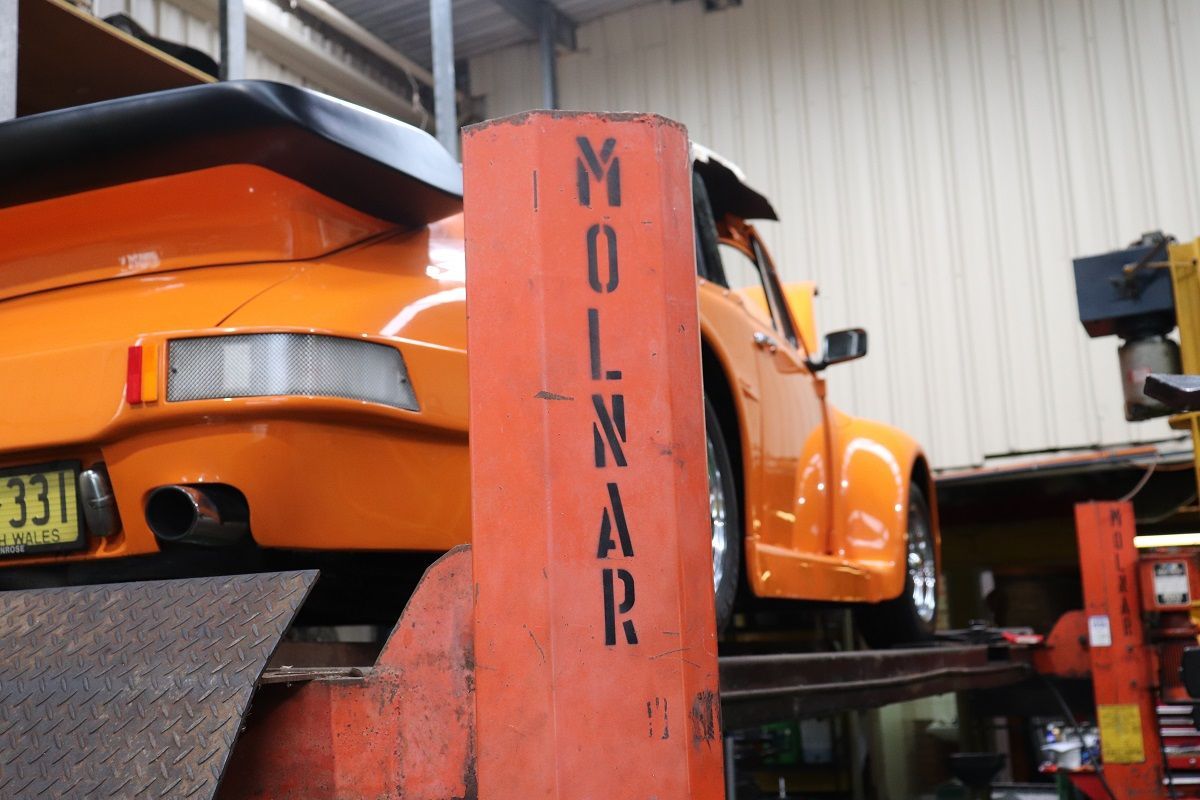 Orange Porsche 911 On Car Lift In Auto Shop — Ballina Car Centre in Ballina, NSW