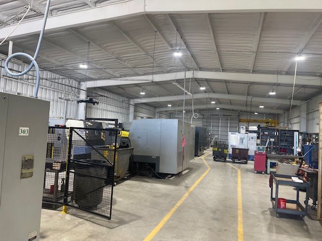 A manufacturing workshop floor with large industrial machinery and marked yellow pathways on a concrete floor.