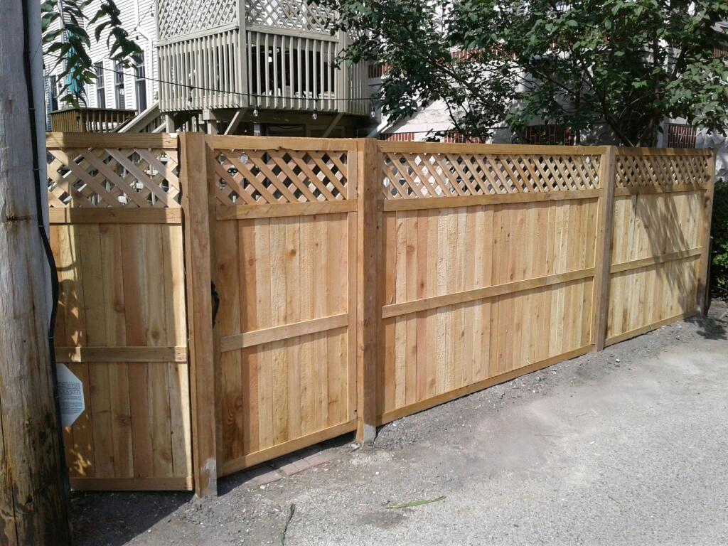 new cedar wood fence installation with top ribbon pattern , unfinished with paint, natural wood.