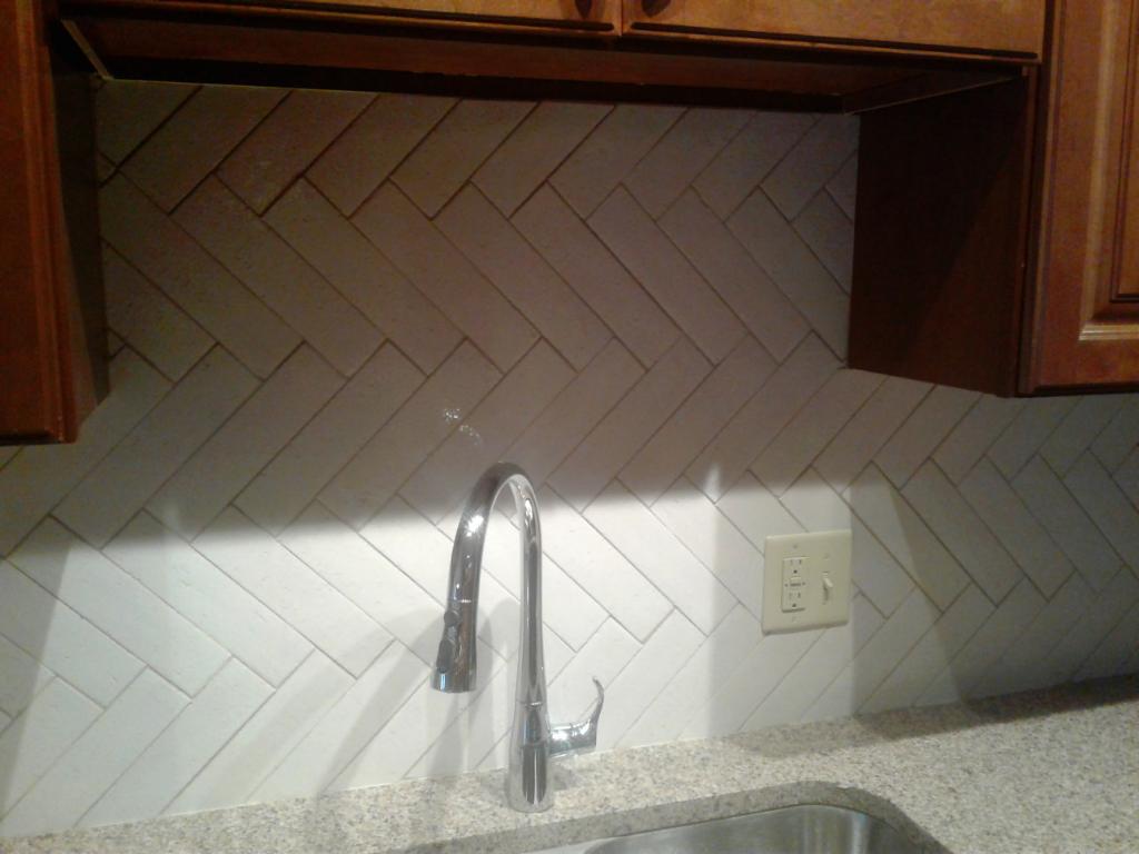 new kitchen sink faucet installation with wood countertop and new backdrop.