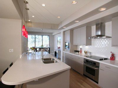 classy white finish on a home kitchen remodel with brand new countertops, wall tile, lighting, and cabinets done by experienced and professional handymen.
