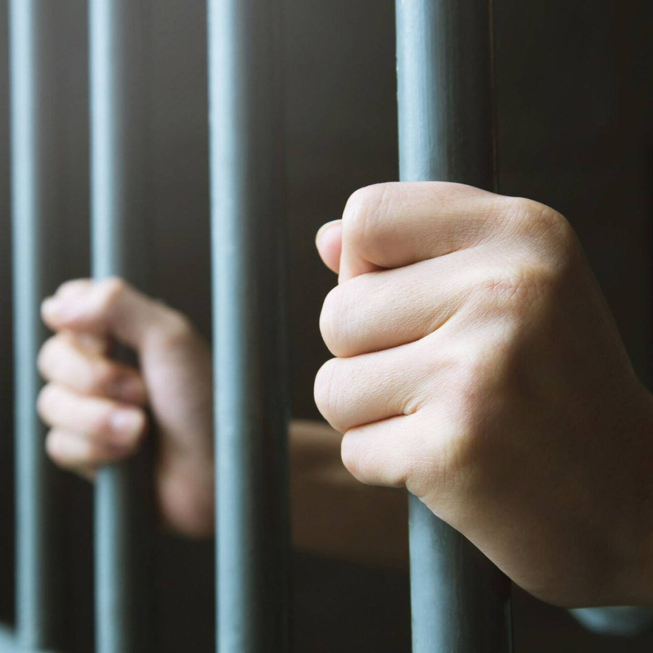 Hands holding prison bars — Live Oak, FL — Chauncey Bail Bond Inc