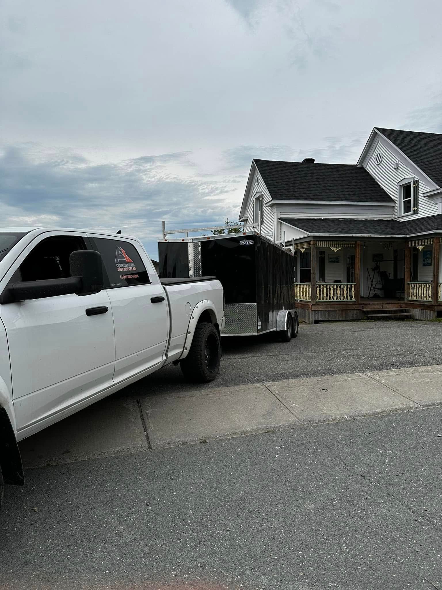 Une camionnette blanche garée à côté d'une maison avec un porche, sous un ciel nuageux.