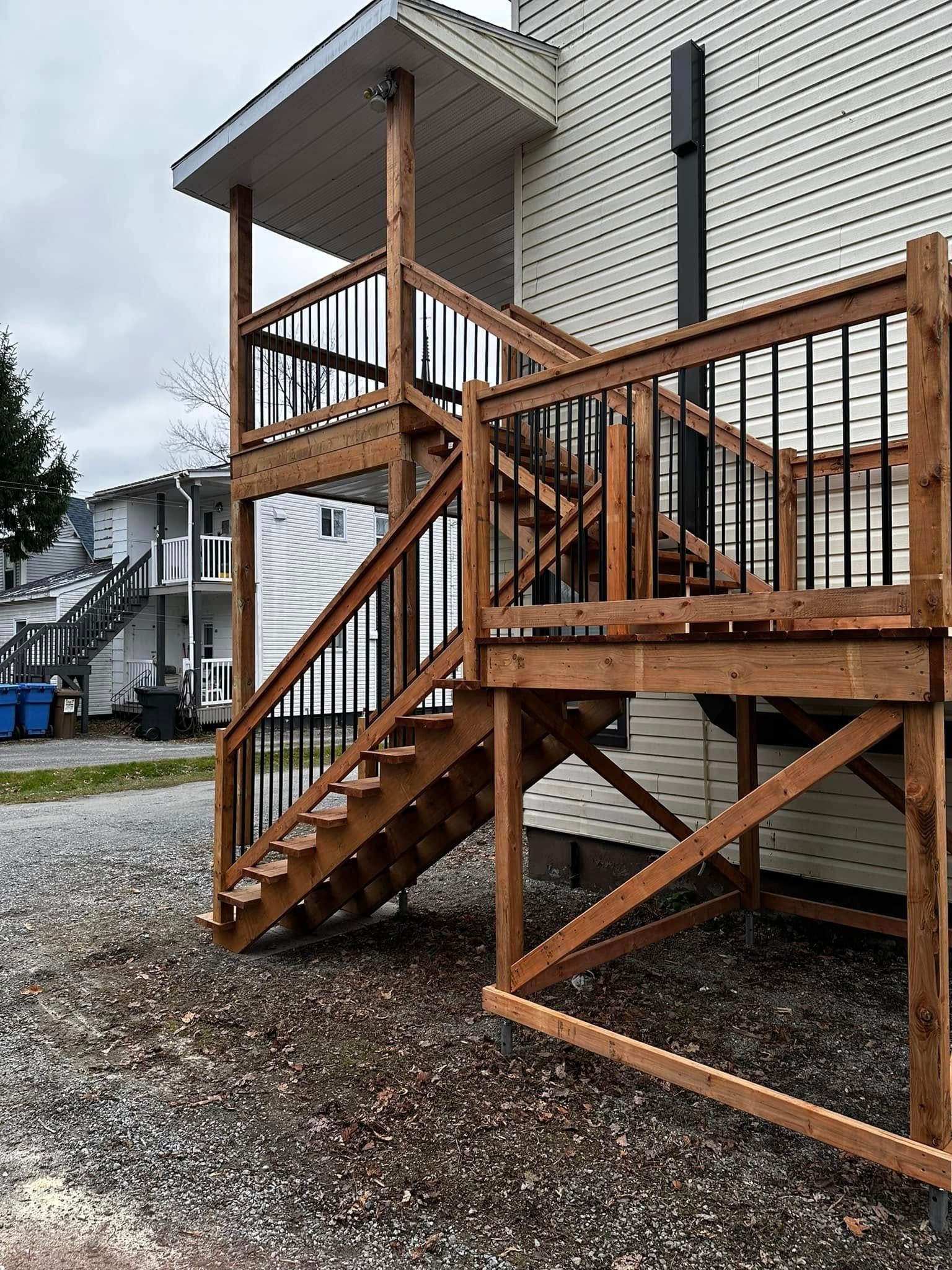 Escalier extérieur en bois et terrasse à côté d'un immeuble d'appartements beige sur un sol en gravier