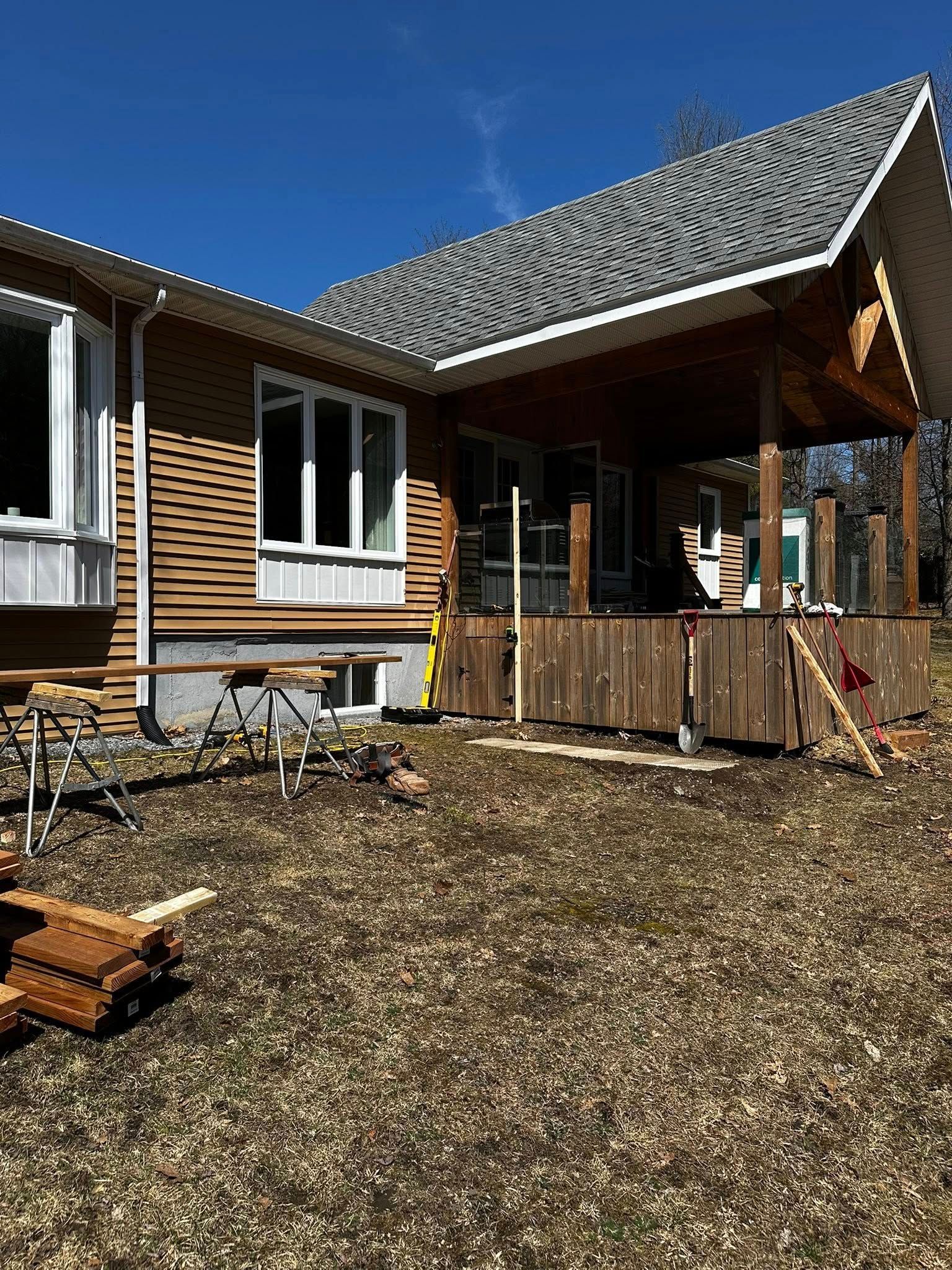 Maison de style chalet en rondins avec porche en bois et cour brune sous un ciel bleu clair