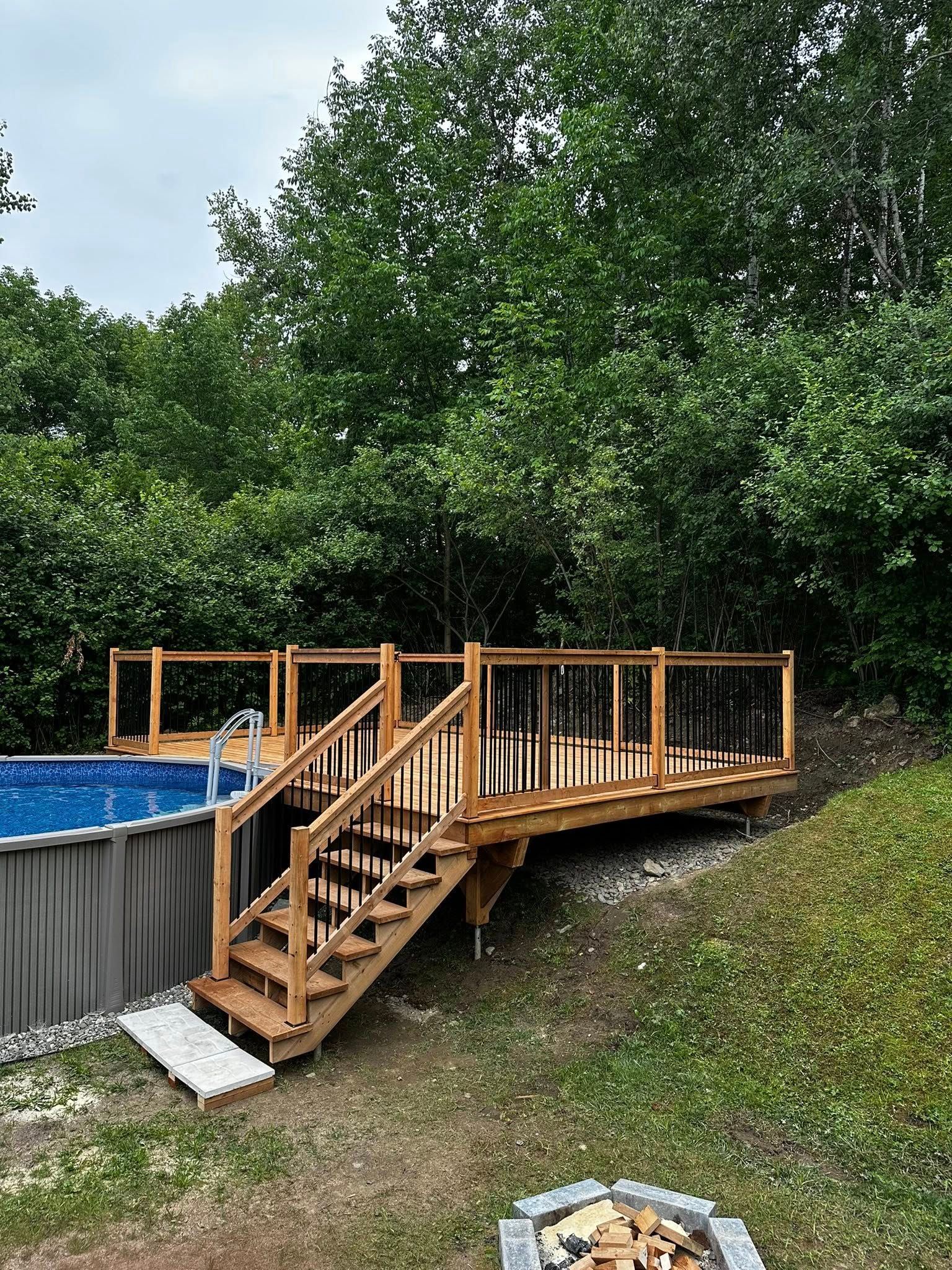Terrasse et escalier en bois jouxtant une piscine hors sol dans un jardin gazonné, avec des arbres en arrière-plan.