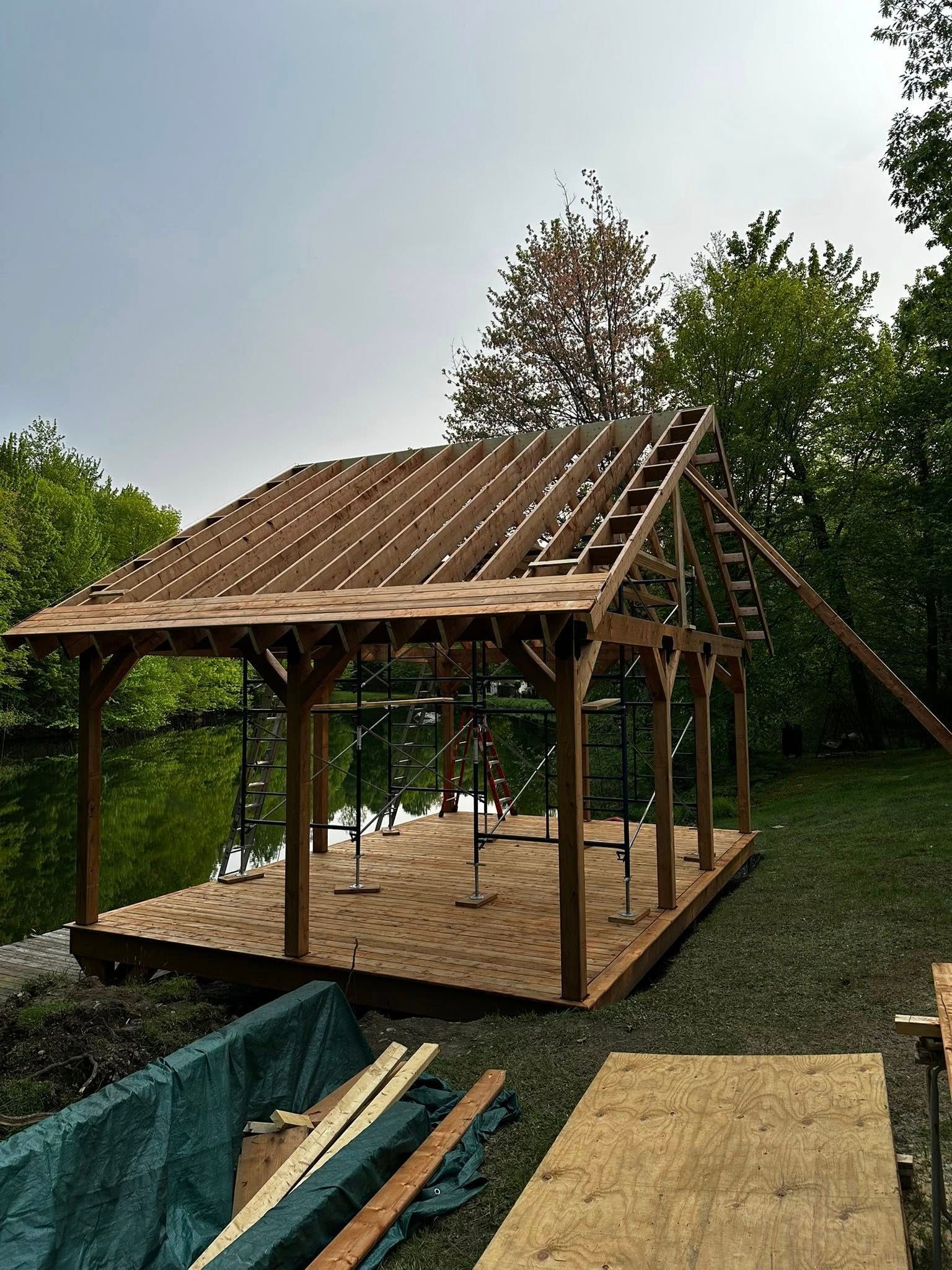 Charpente de cabane en bois partiellement construite avec fermes de toit dans une cour extérieure gazonnée