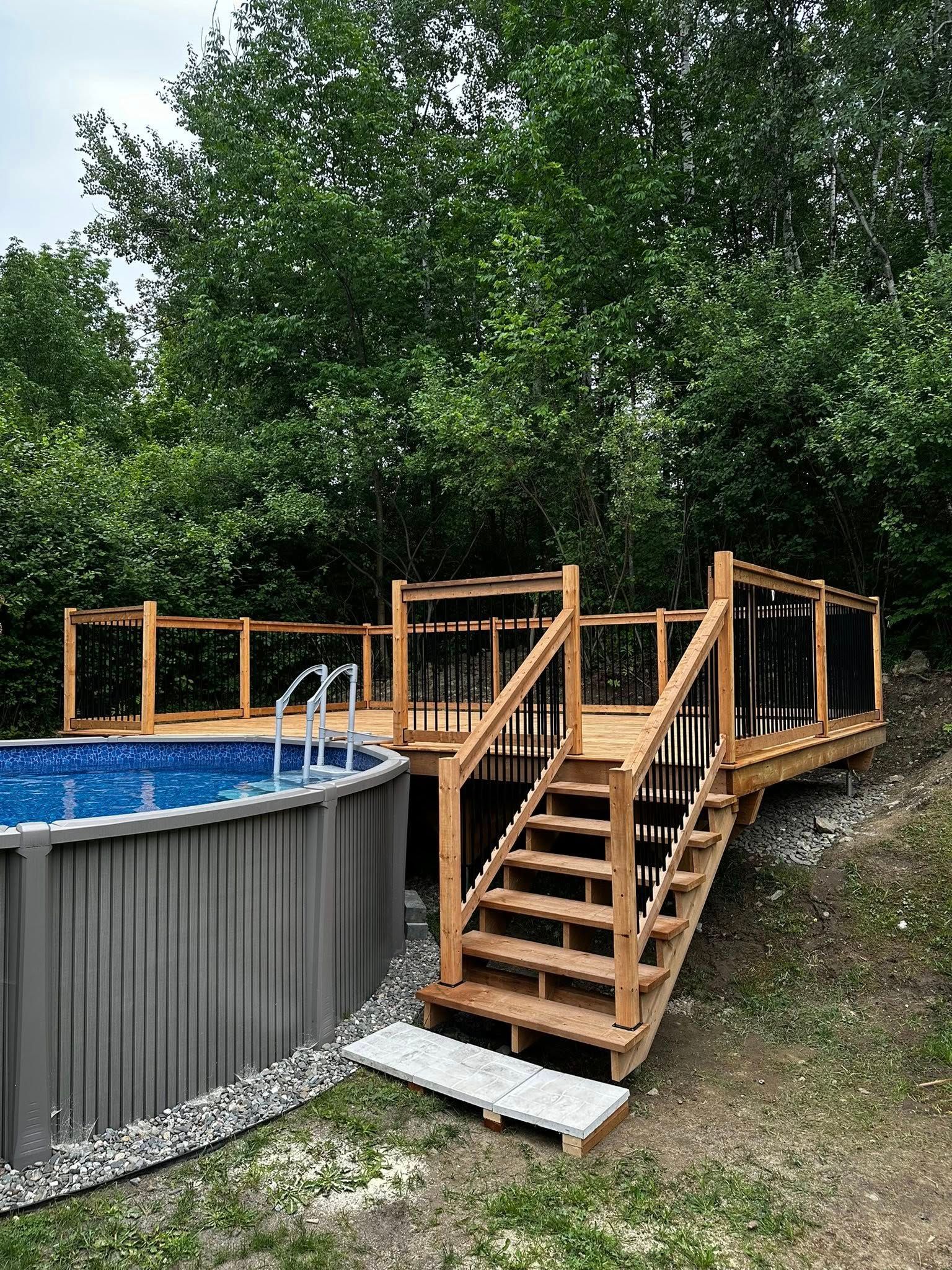 Piscine hors sol dans le jardin avec terrasse et escalier en bois, entourée d'arbres.